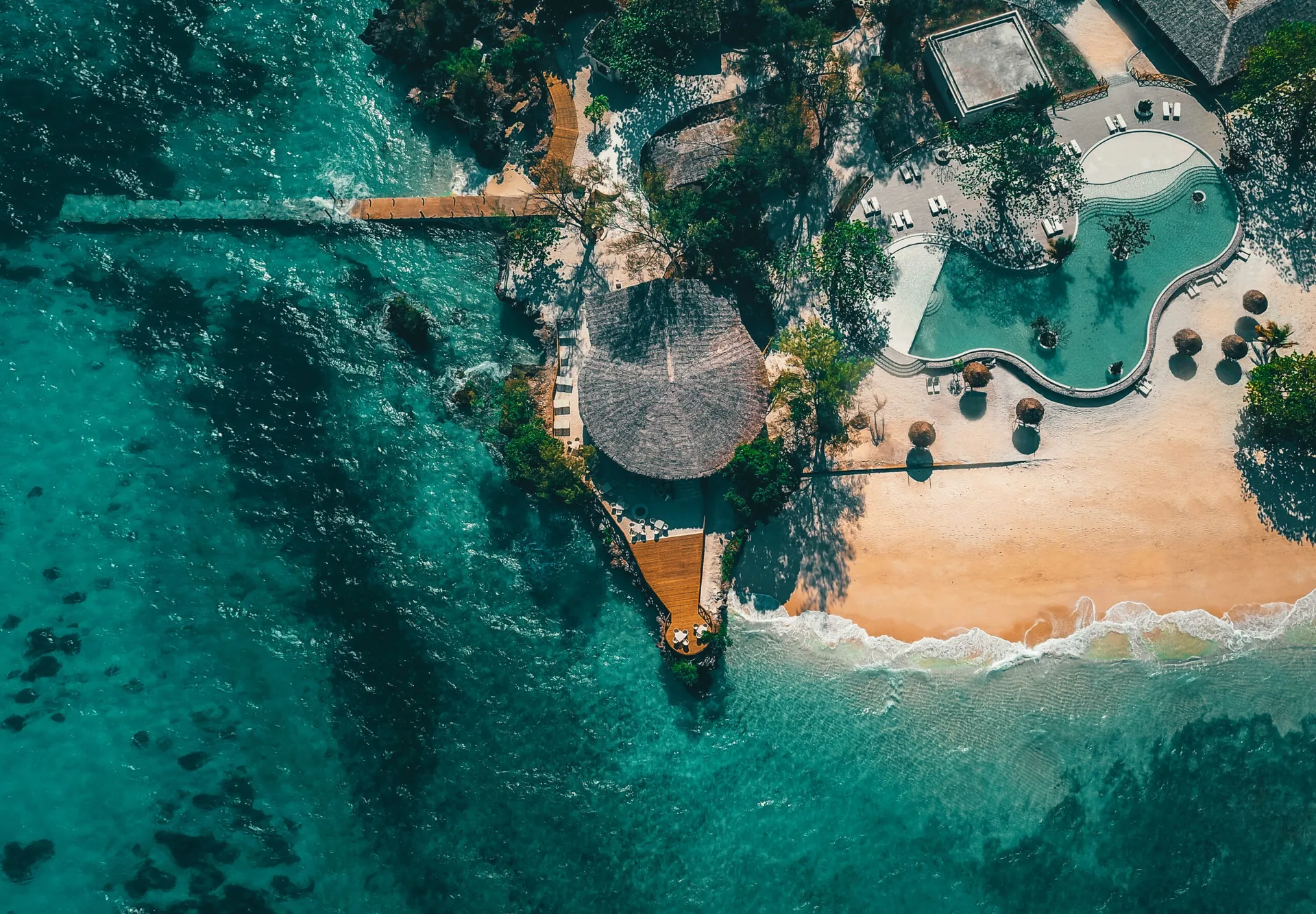 Aerial view of an island resort pool beside the Indian Ocean